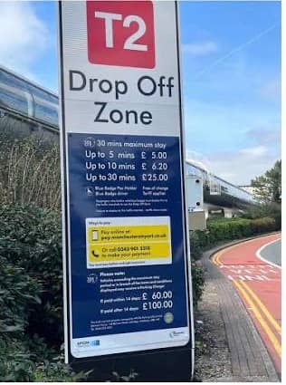 A Terminal 2 drop-off zone sign listing the tariffs and the parking charge amounts.